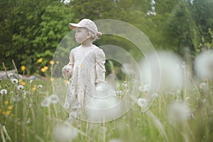 Beautiful child with dandelion flowers in park in summer. Happy kid having fun outdoors.