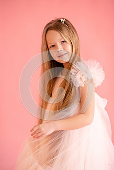 Beautiful child girl 7-8 year old wearing trendy dress posing over pink background. Looking at camera. Fashionable