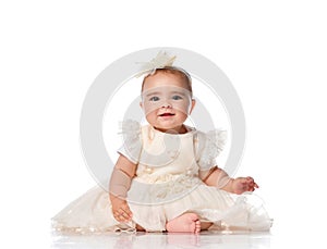 Beautiful child girl in a festive dress and headband sitting on the floor. Toddler toddler looking at camera studio portrait shot