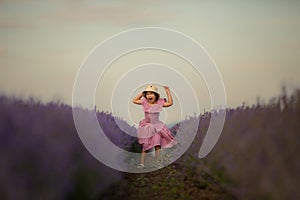Beautiful child girl in a hat jumps in the middle of a lavender field