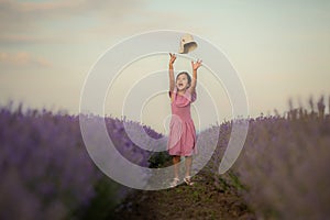 Beautiful child girl in a hat jumps in the middle of a lavender field