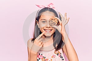 Beautiful child girl holding cookie smiling happy pointing with hand and finger