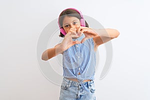 Beautiful child girl listening to music using headphones over isolated white background smiling in love showing heart symbol and