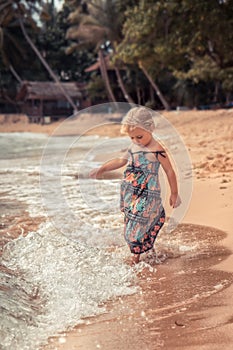 Beautiful child girl playing with waves on beach tropical island during summer holidays concept carefree childhood travel lifestyl