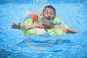 Beautiful child girl in swimming pool relax swim on inflatable ring. Summer holiday, vacation and happy childhood