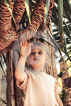 Beautiful child girl touching palm tree concept saving nature lifestyle