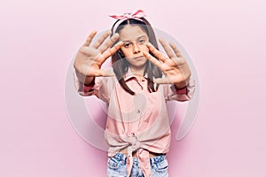 Beautiful child girl wearing casual clothes doing frame using hands palms and fingers, camera perspective