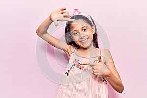 Beautiful child girl wearing casual clothes smiling making frame with hands and fingers with happy face