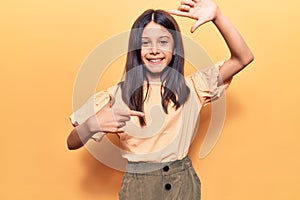 Beautiful child girl wearing casual clothes smiling making frame with hands and fingers with happy face