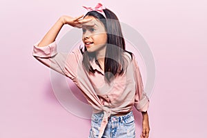 Beautiful child girl wearing casual clothes very happy and smiling looking far away with hand over head