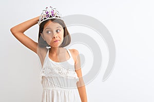 Beautiful child girl wearing princess crown standing over isolated white background confuse and wonder about question