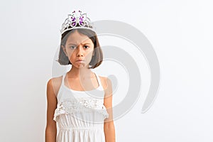 Beautiful child girl wearing princess crown standing over isolated white background depressed and worry for distress, crying angry