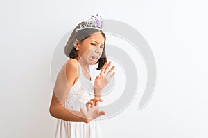 Beautiful child girl wearing princess crown standing over isolated white background disgusted expression, displeased and fearful