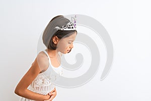 Beautiful child girl wearing princess crown standing over isolated white background with hand on stomach because indigestion,