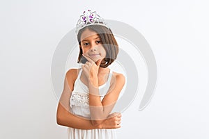 Beautiful child girl wearing princess crown standing over isolated white background looking confident at the camera with smile