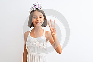 Beautiful child girl wearing princess crown standing over isolated white background showing and pointing up with fingers number