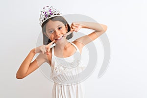 Beautiful child girl wearing princess crown standing over isolated white background smiling cheerful showing and pointing with