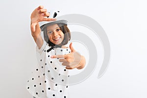 Beautiful child girl wearing security bike helmet standing over isolated white background smiling making frame with hands and