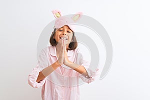 Beautiful child girl wearing sleep mask and pajama standing over isolated white background begging and praying with hands together