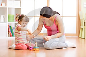 Beautiful child playing with toys with happy mother indoors