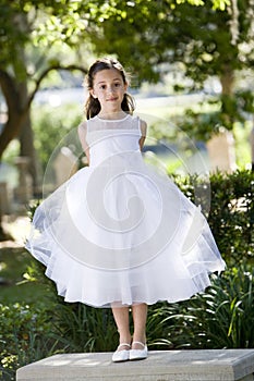 Beautiful child in white dress on park bench photo