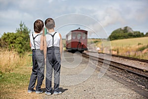 Beautiful children, dressed in vintage clothes, enjoying old steam train on a hot summer day