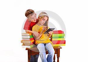 Beautiful children read e-book surrounded by books