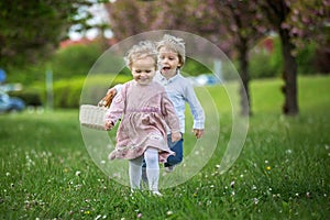 Beautiful children, toddler boy and girl, playing together in cherry blossom garden, running together and smiling with joy. Kids