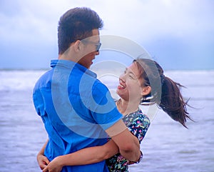 beautiful Chinese Asian couple with woman hug her boyfriend romantic and cuddle on the beach smiling in dating and romance photo