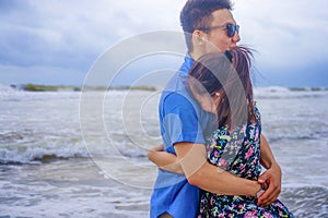 beautiful Chinese Asian couple with woman hug her boyfriend romantic and cuddle on the beach smiling in dating and romance