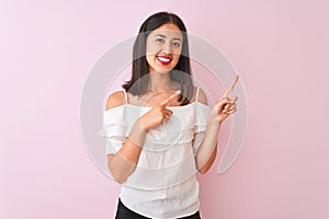 Beautiful chinese woman wearing white t-shirt standing over isolated pink background smiling and looking at the camera pointing