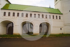 Beautiful Christian white church hall with archs, green roof beside green grass lawn and asphalt road.