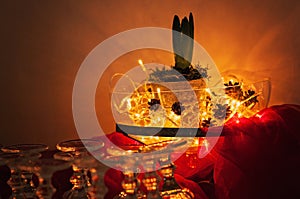 Beautiful Christmas arrangement with a potted Hyacinth flower, fairy lights and pinecones in a glass bowl. Around it some wine