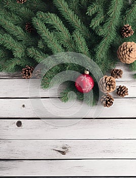 Beautiful Christmas background with a border of fir branches, red baubles, pine cones