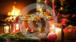 Beautiful christmas background with candles and lanterns on wooden table against burning fireplace