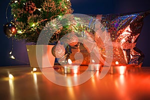 Beautiful Christmas background with golden candle light on a table and copy space against Christmas tree and present