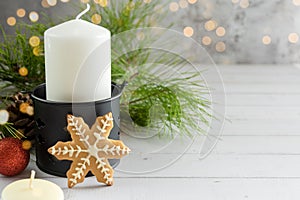 Beautiful Christmas background, a large white candle in a candlestick, gingerbread, fir branches and toys on a wooden background