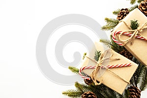 Beautiful Christmas background with two gift boxes, decorate with pine branch and pine cone over white background. Top view with c