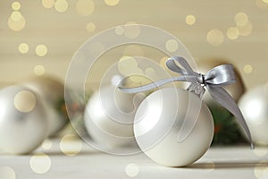 Beautiful Christmas ball with silver bow on table, bokeh effect