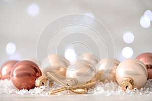 Beautiful Christmas balls on snow against blurred festive lights. Space for text