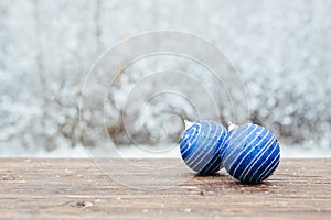 Beautiful Christmas bauble decorations lie on the wooden table over snow covered forest background