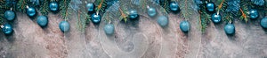 Beautiful Christmas border, fir branches decorated blue balls and tinsel on a dark textured rustic background. Top view, flat lay