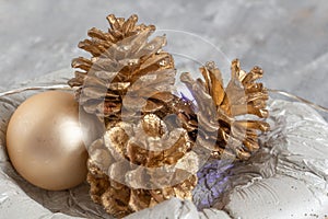 beautiful christmas decor in silver and gold tones, pine cones in a concrete bowl, new year lights, stylish and modern