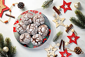 Beautiful Christmas flat lay with traditional cocoa crinkle cookies in a colorful plate, surrounded by Christmas ornaments and