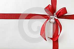 Beautiful Christmas gift present with bright red bow and silver wrapping paper background border