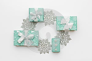 Beautiful christmas gifts and silver snowflakes isolated on white background. Turquoise colored wrapped xmas boxes.