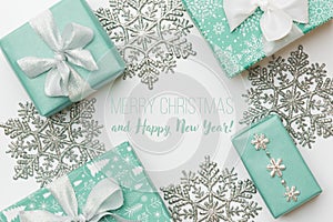 Beautiful christmas gifts and silver snowflakes isolated on white background. Turquoise colored wrapped xmas boxes.