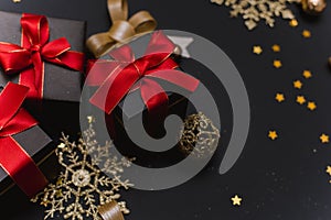 Beautiful Christmas golden snowflakes with gifts on a dark black background. Flat lay. Copy space.