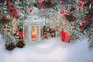 Beautiful Christmas lantern with candle and fir branches with cones and red berries in snow. Atmospheric winter scene with copy