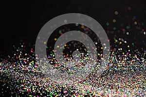 Beautiful Christmas light background. Abstract glitter bokeh and scattered sparkles in gold, on black